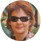 a woman in sunglasses smiling in a garden